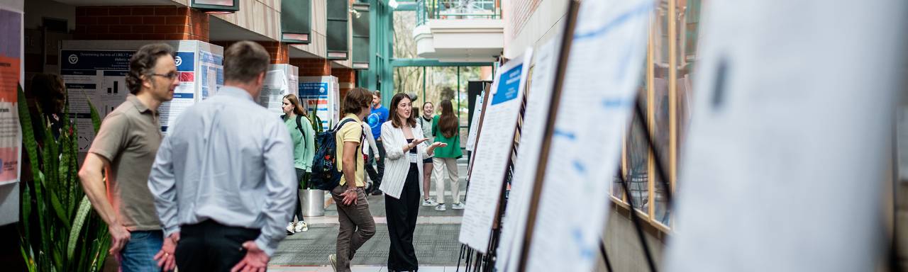 A handful of GVSU faculty, staff and students stand by poster presentations of research projects.